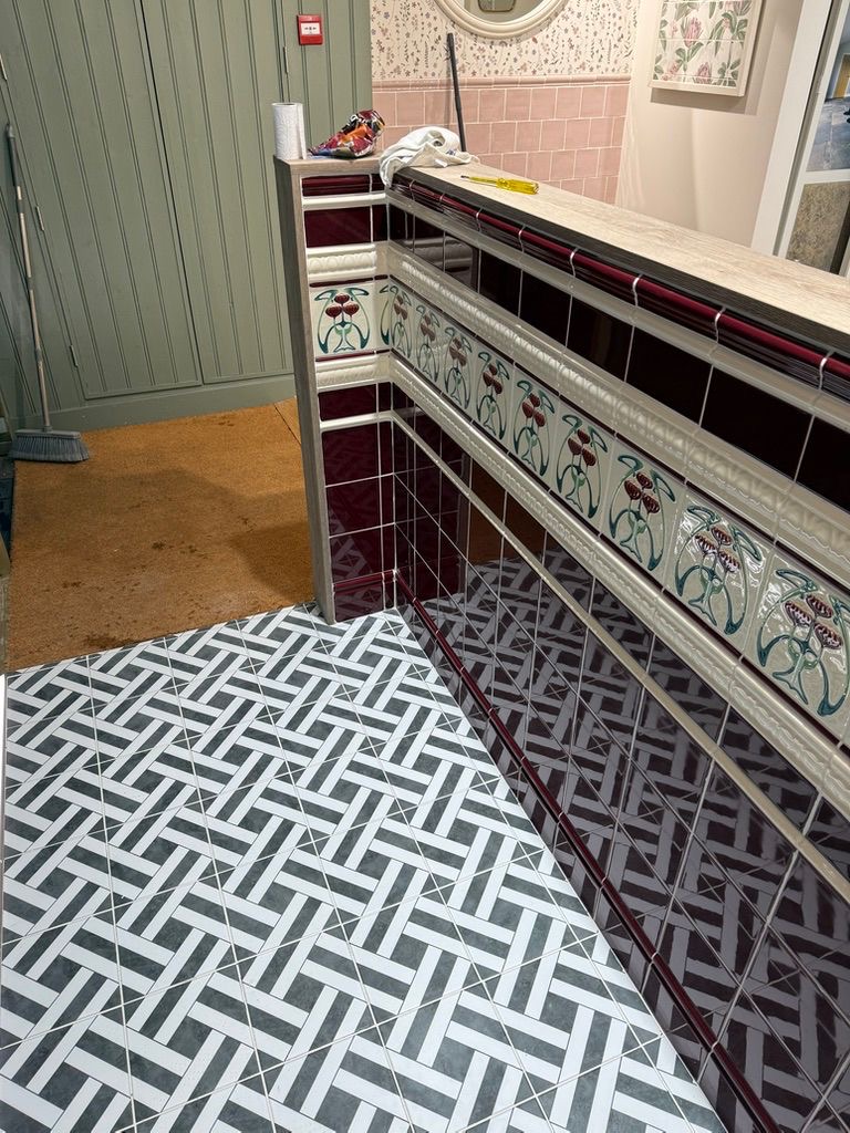 Corner detail of heritage burgundy tiling with polished chrome trim and geometric mosaic flooring, King's Road showroom