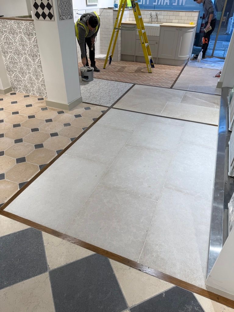 Installation in progress: large-format stone floor tiles with brass trims meeting octagon and chequerboard displays, Clay and Rock