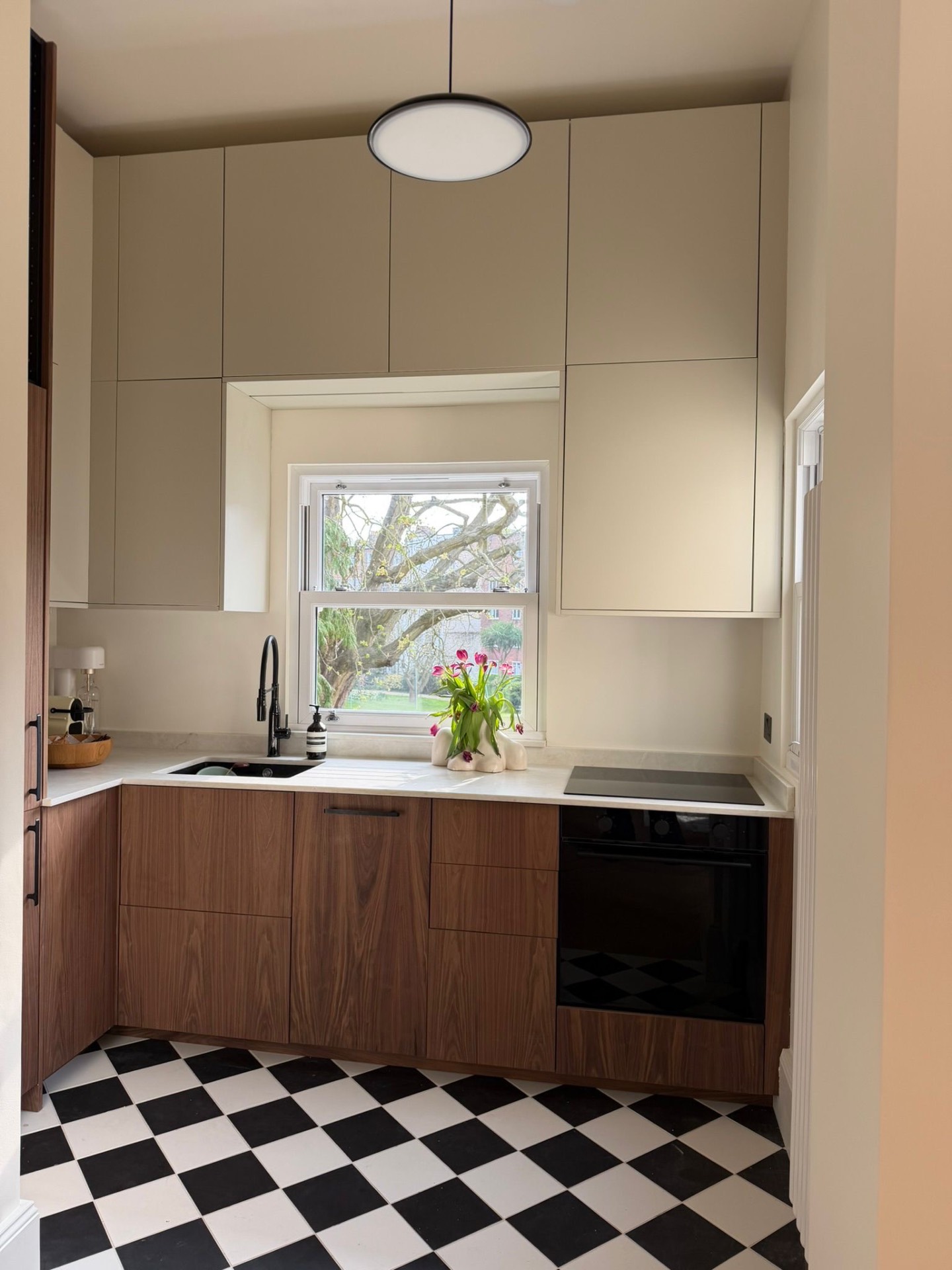 Compact walnut and stone kitchen with monochrome checkerboard floor