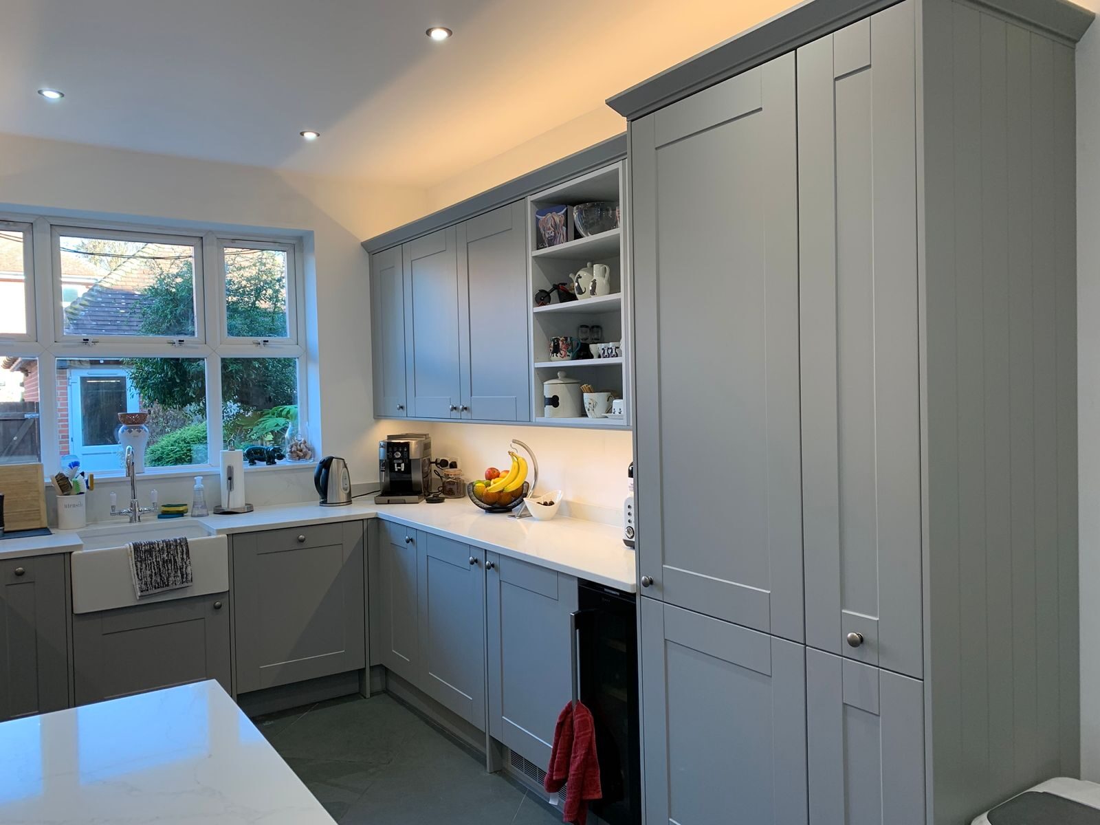Pale grey shaker kitchen with white quartz worktops, Belfast sink and garden bay window