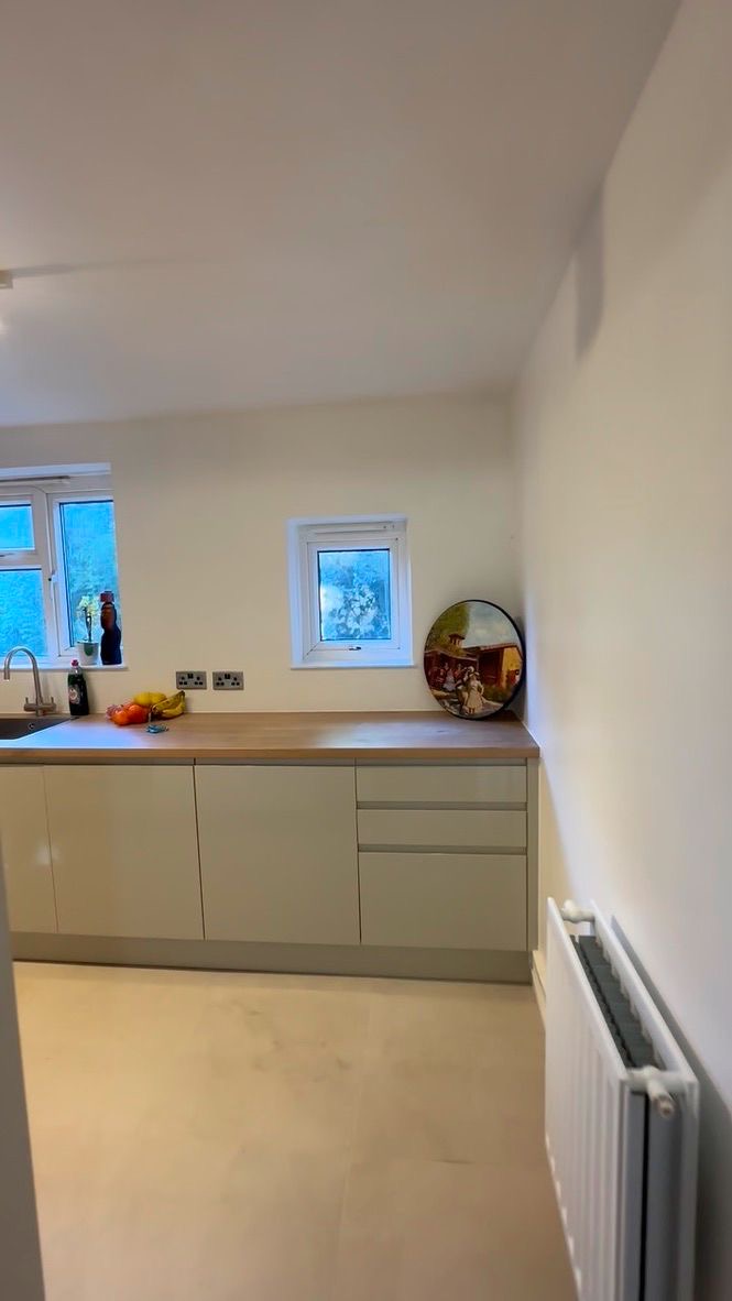 Bright open kitchen with timber worktop, twin windows and calm neutral walls, central London apartment