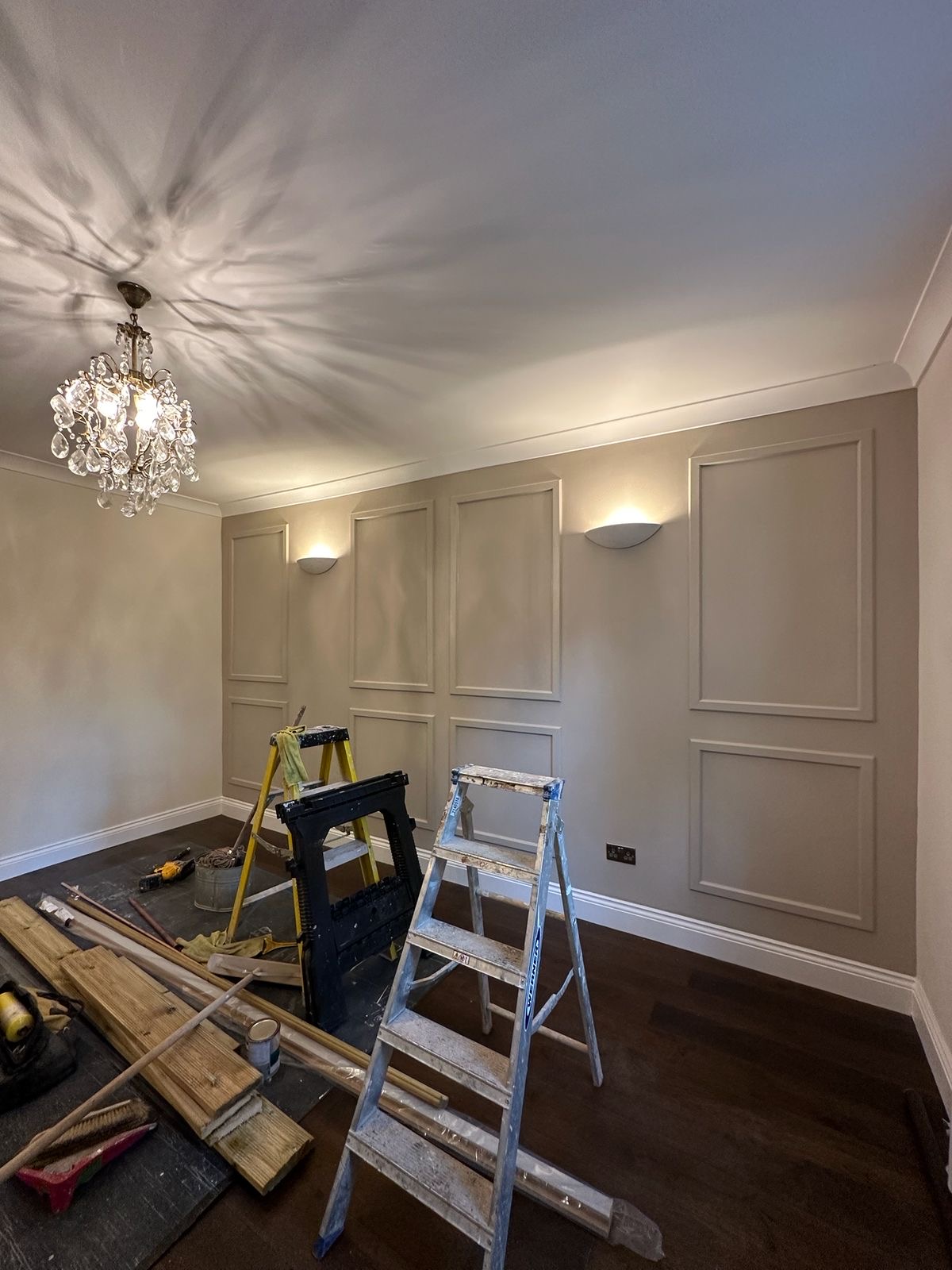 Panelled reception room in soft taupe with crystal chandelier and dark timber floor, Kennington