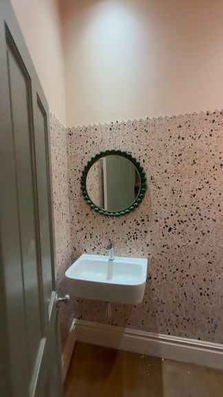 Small wall-hung basin against picket terrazzo tiling with round green beaded mirror, SW6