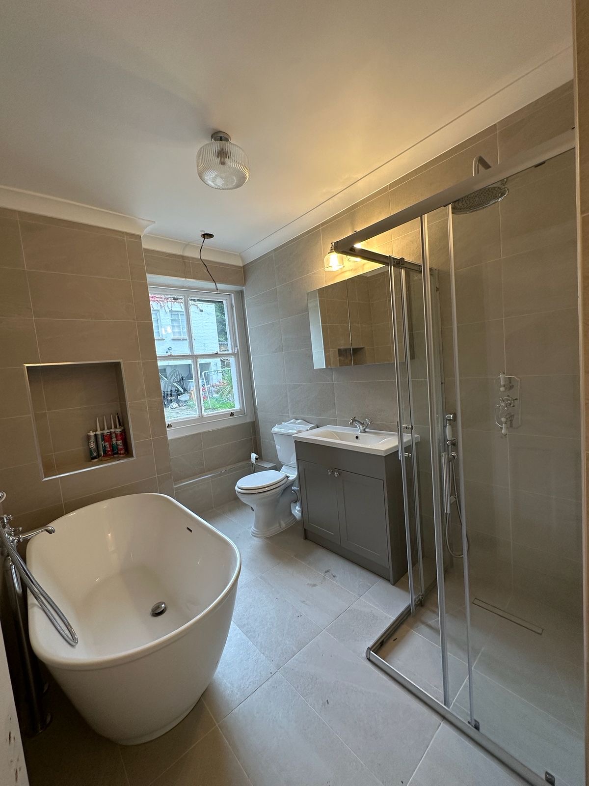 Finished family bathroom with stone tiling, walk-in shower and traditional basin, SE1